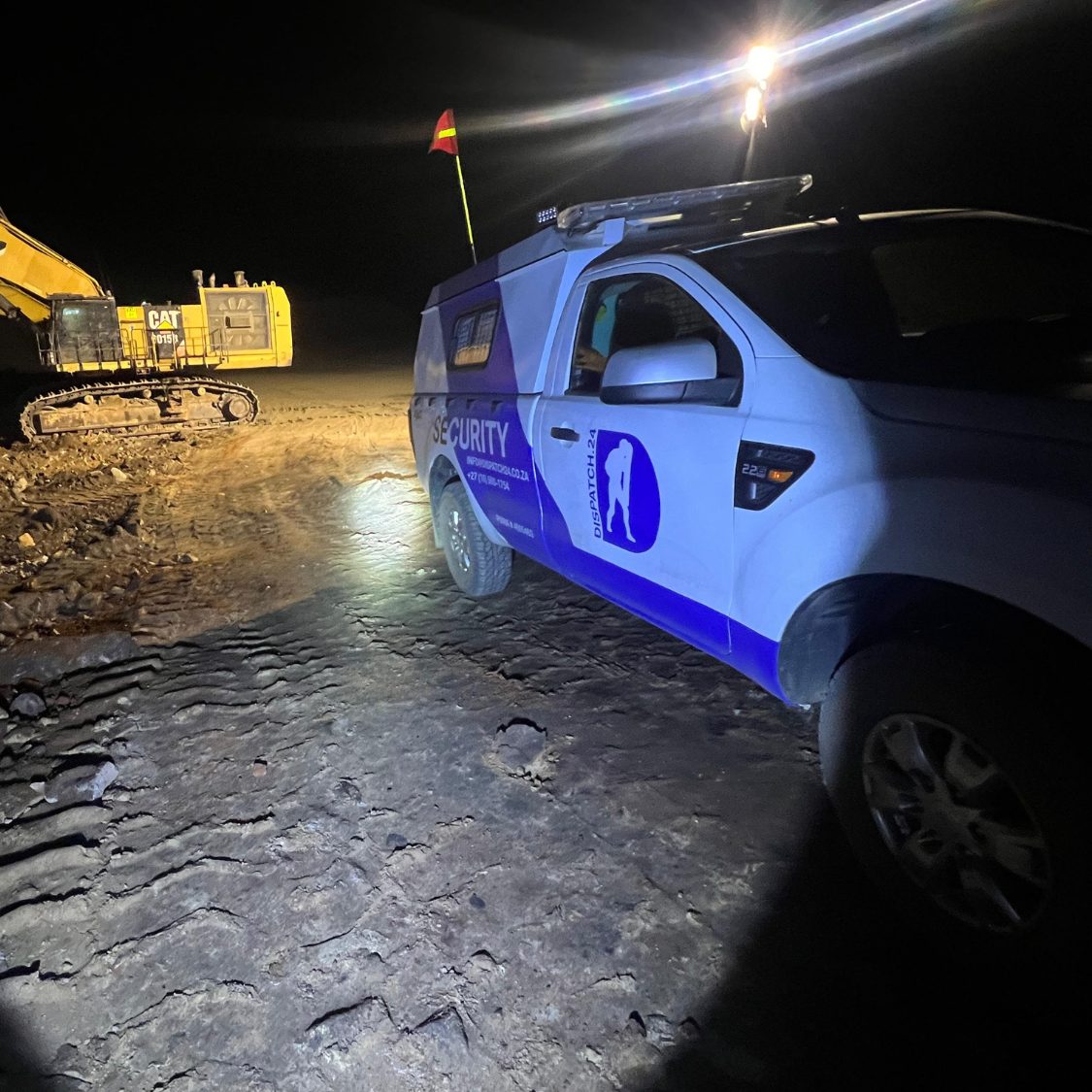 Patrol vehicle beside working plant on a mine at night